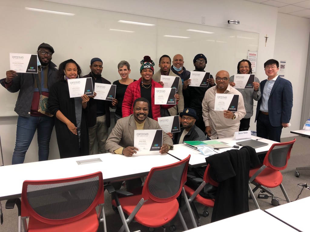 thirteen people, many of whom are smiling; ten are holding certificates of completion for Negotiation Works.